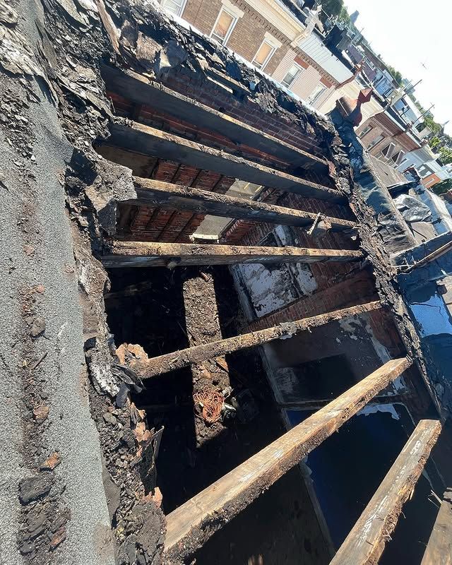 The roof of a building is being demolished and the wooden beams are missing.