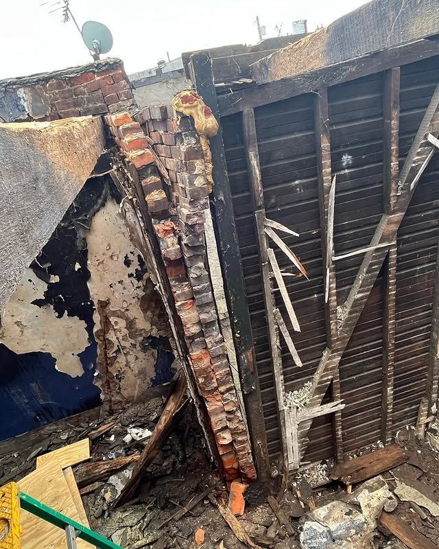 A brick wall is being demolished and a satellite dish is sitting on top of it.