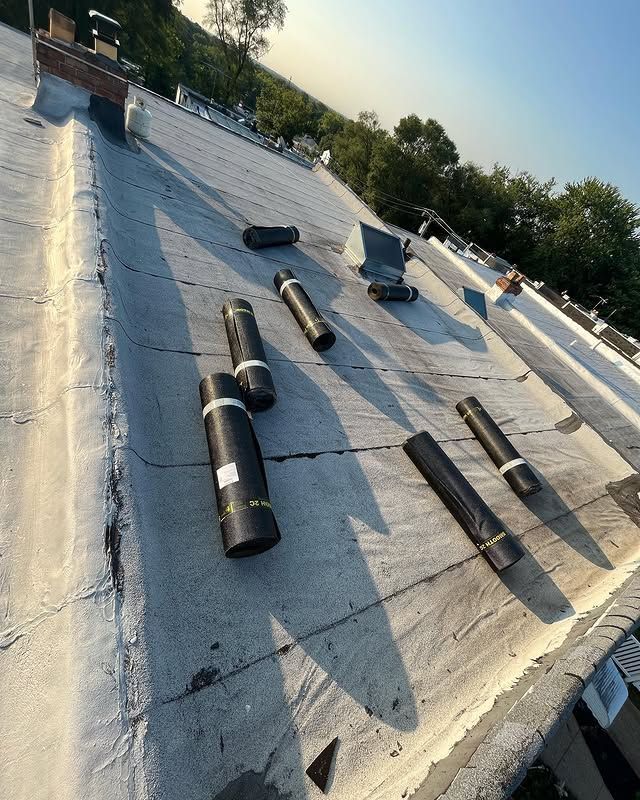 A roof with a lot of rolls of roofing material on it.