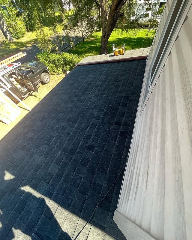 A black roof is being installed on the side of a house.