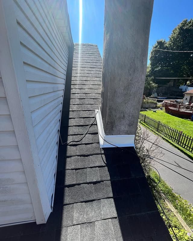 A chimney on the roof of a house next to a white house.