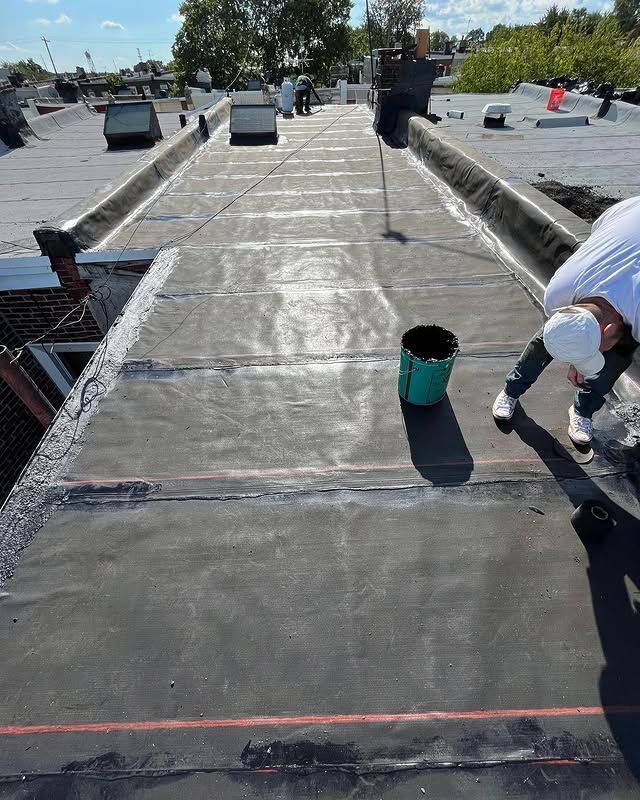 A man is painting a roof with a bucket of paint.