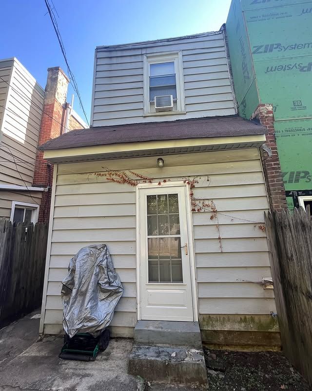 A small white house with a motorcycle cover on the side of it.