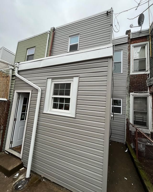 The back of a house with siding and a drainpipe.