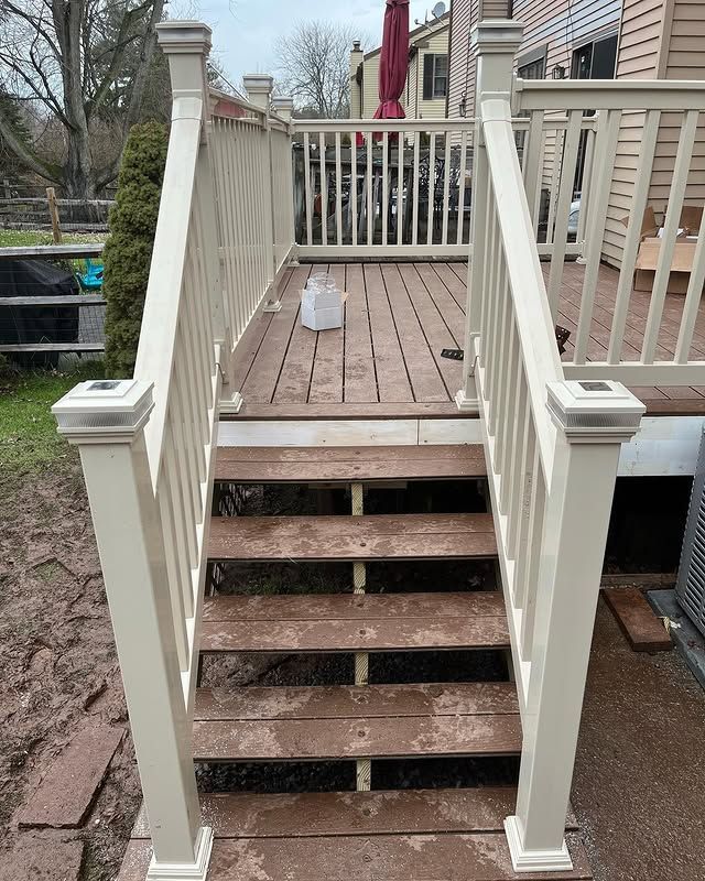 A deck with stairs leading up to it and a white railing.