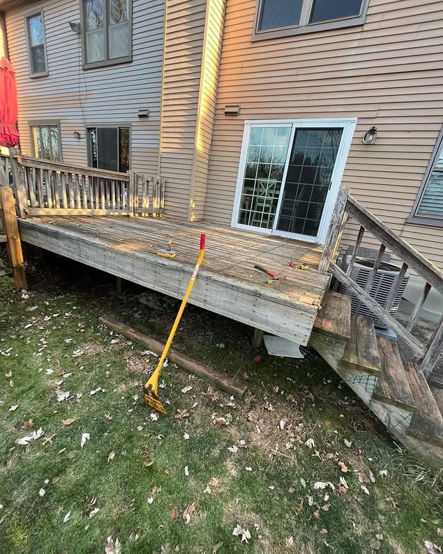 A wooden deck with stairs and a rake in front of a house.