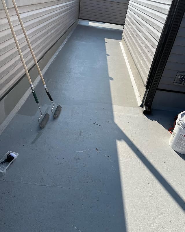 A concrete walkway with a bucket of paint and a broom.