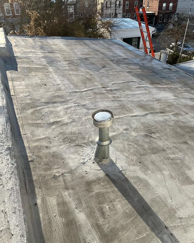A roof with a chimney on it and a ladder in the background.