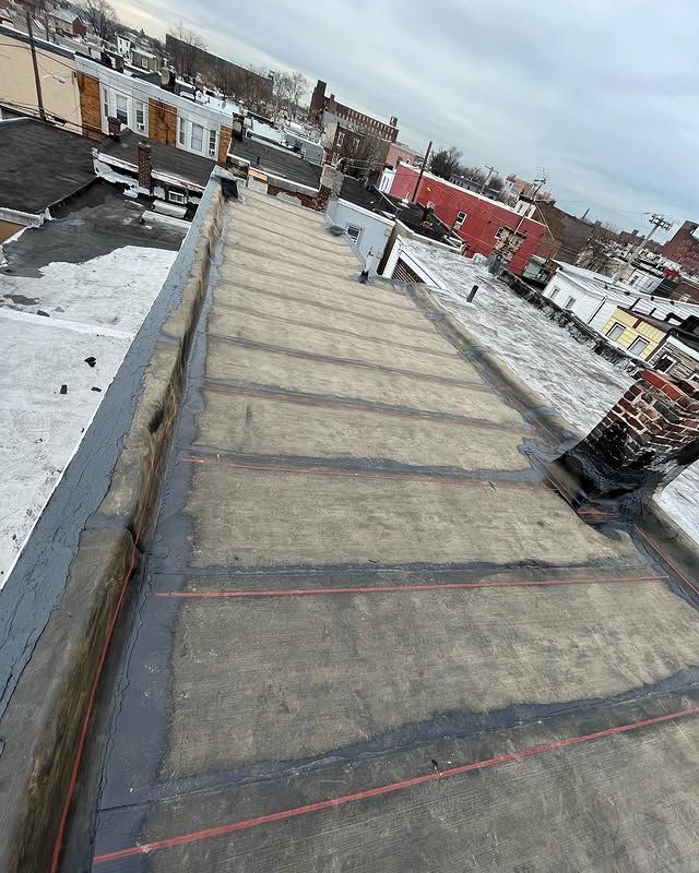 A roof with a lot of snow on it and a lot of buildings in the background.