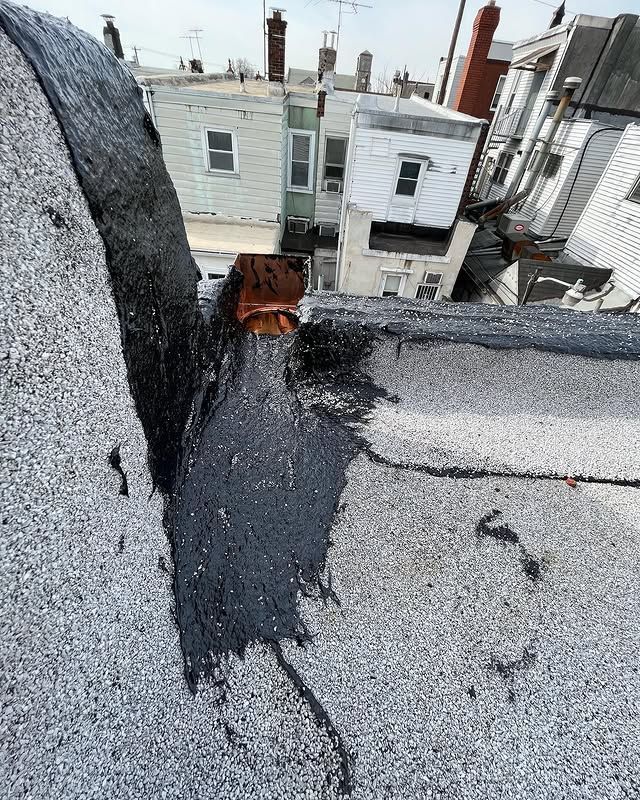 A roof with a hole in it and a lot of buildings in the background.