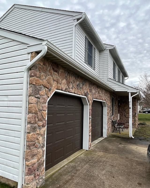 A house with two garage doors and a stone wall.