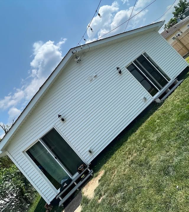 A white house is sitting on top of a lush green field.