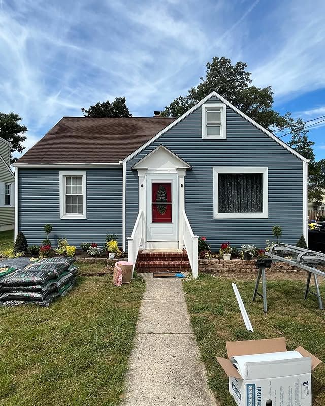 A blue house with a red door is being painted.