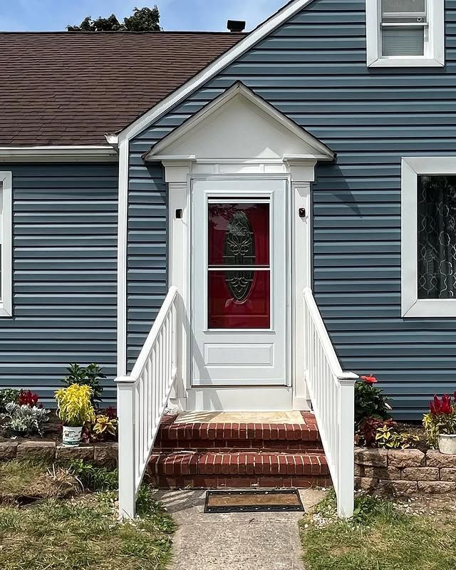 A blue house with a white door and stairs leading to it.