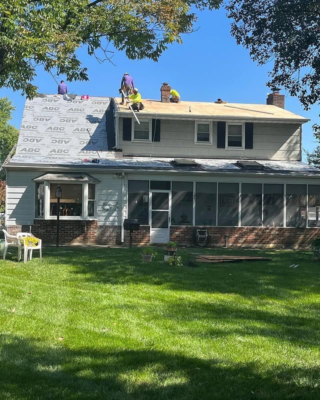 A group of people are working on the roof of a house.