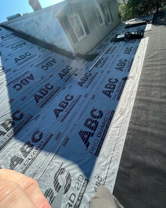 A person is holding a piece of abc roofing paper on top of a roof.