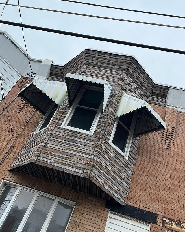 A brick building with a wooden roof and two windows.