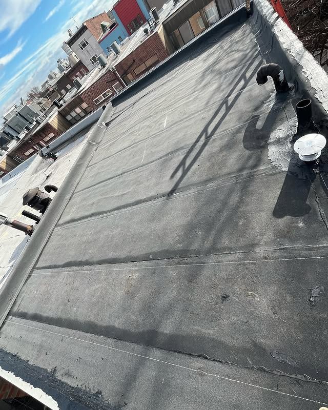 The roof of a building with a black roof and a white chimney on it.