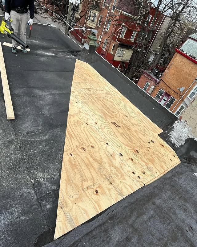 A person is standing on a roof with a vacuum cleaner.