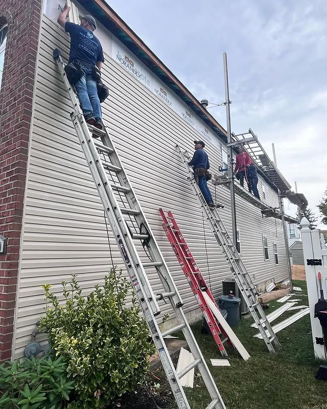 A group of men are working on the side of a house.