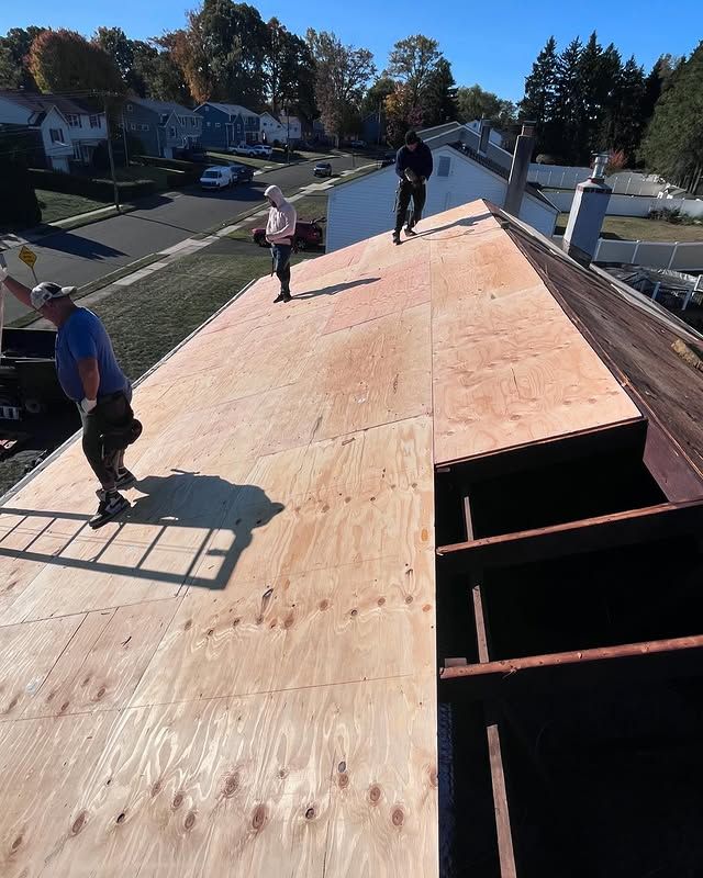 Two men are standing on top of a wooden roof.