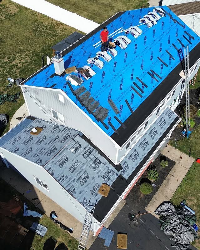 An aerial view of a house with a blue roof being installed.