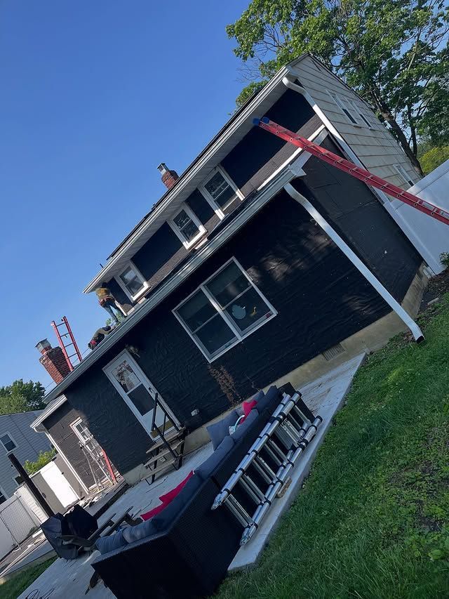 A black house with a ladder in front of it is being painted.
