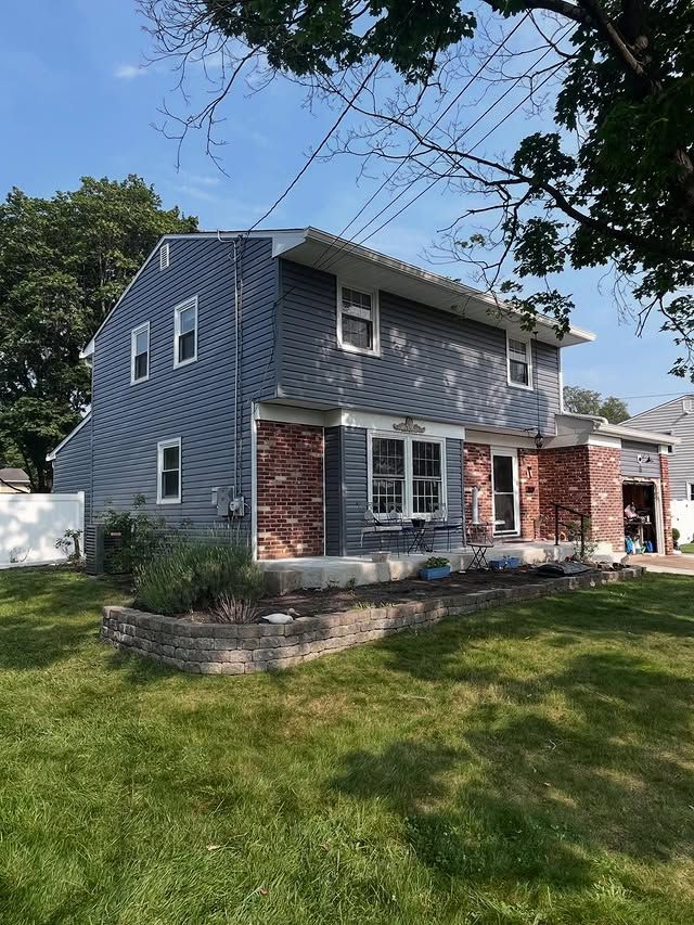 A large house with a lot of windows is sitting on top of a lush green lawn.