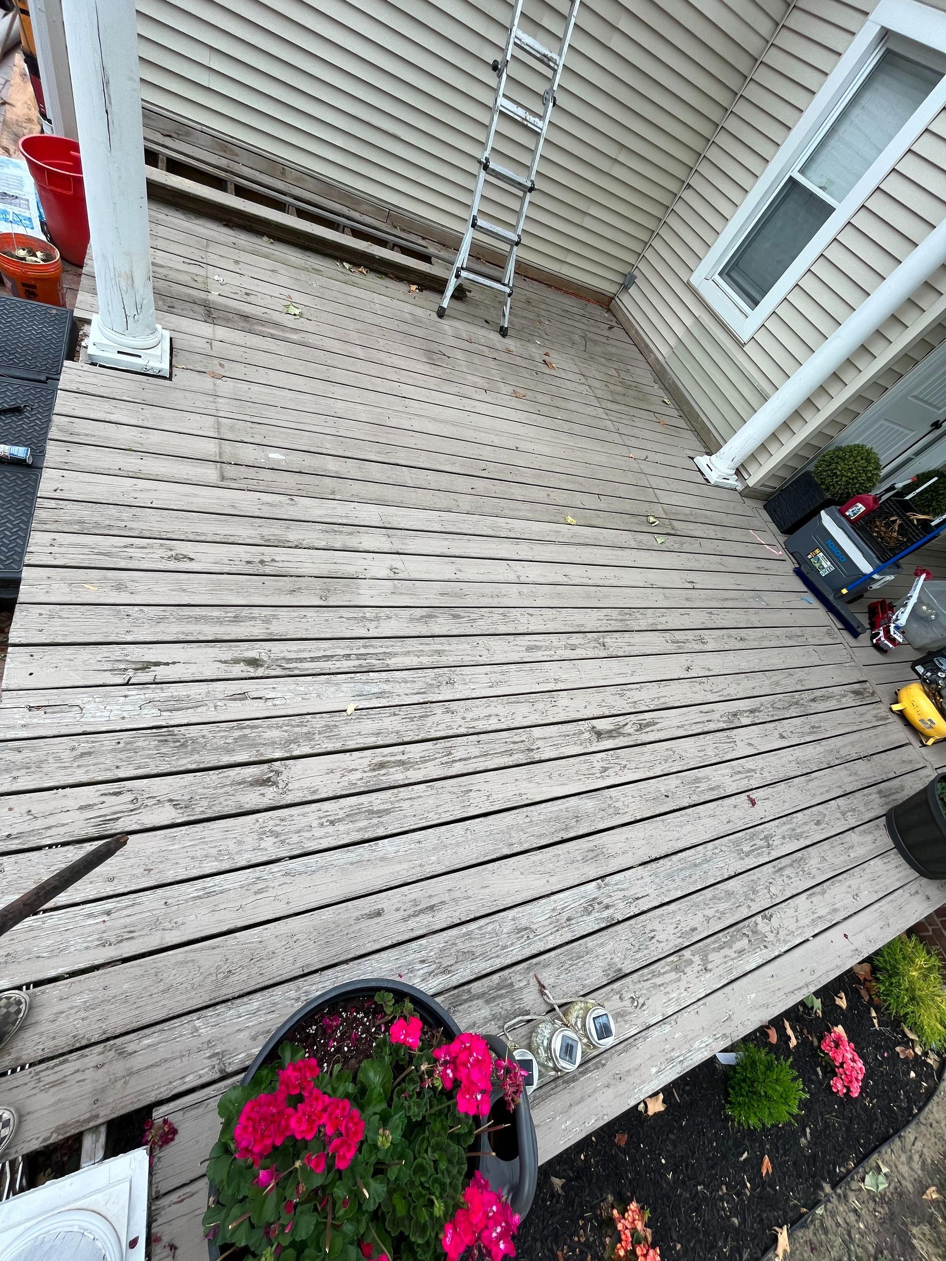 An aerial view of a wooden deck with flowers and a ladder.