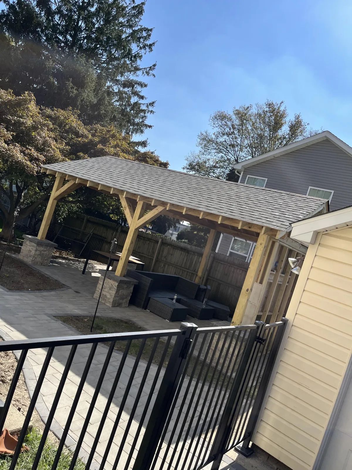 A wooden gazebo in the backyard of a house