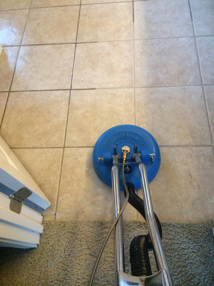 Blue floor cleaner cleaning beige tile floor.