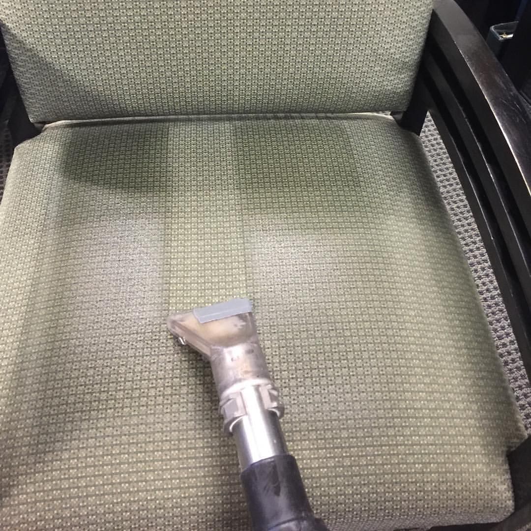 Chair being cleaned with upholstery cleaner; green fabric with a metal nozzle.