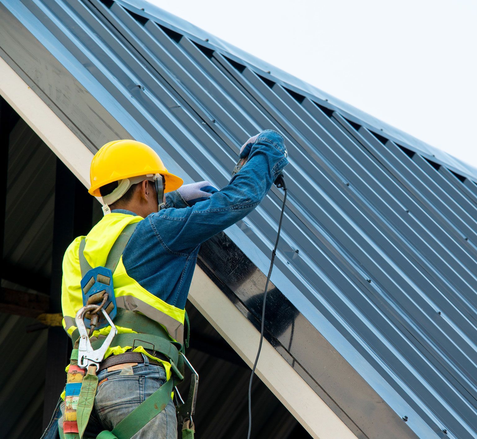 A man is working on a roof with a drill.