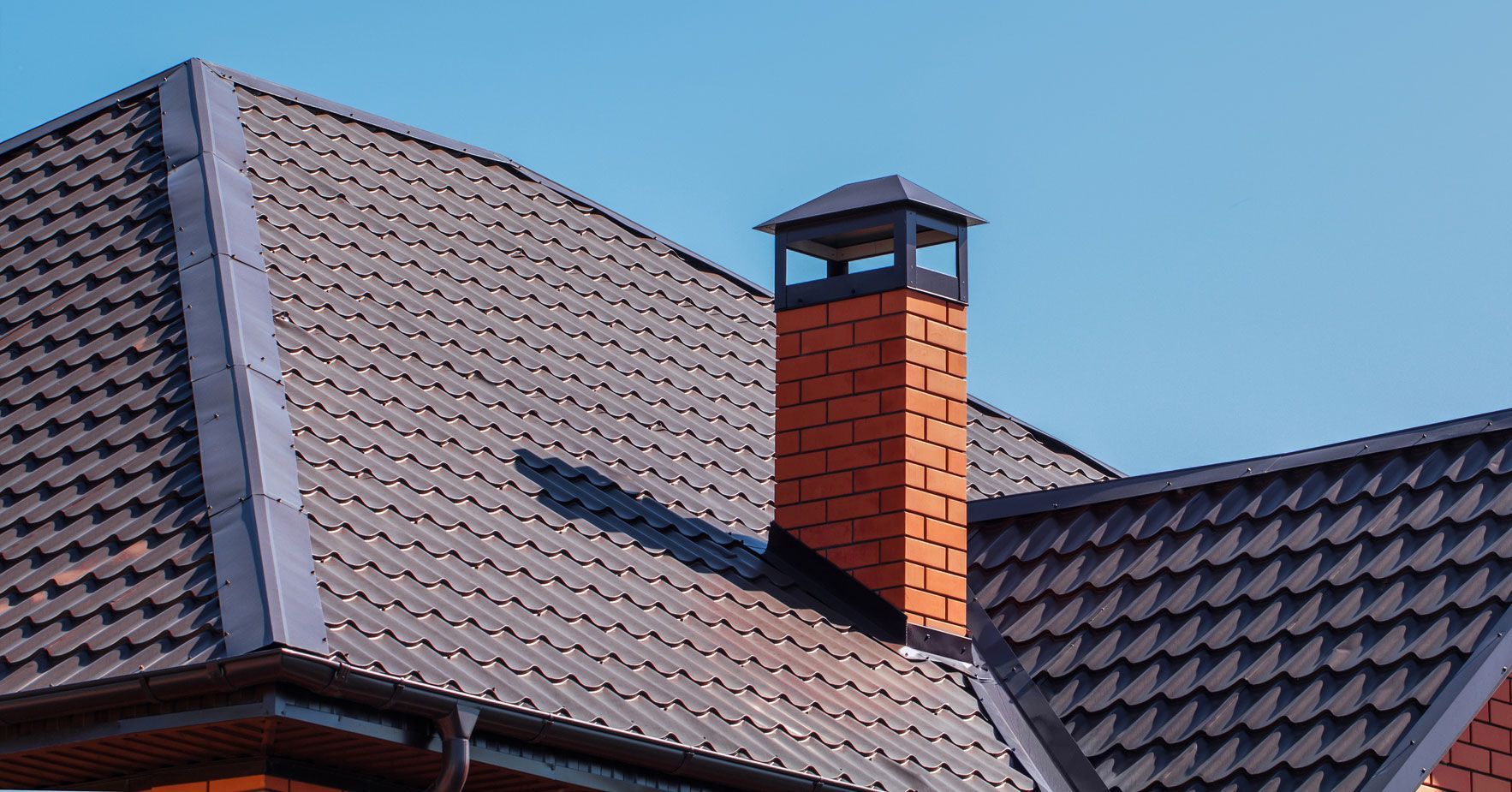 A brick chimney is on the roof of a house.
