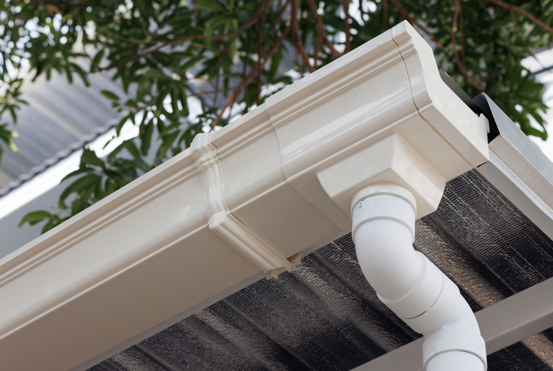 A close up of a white gutter on the roof of a house.