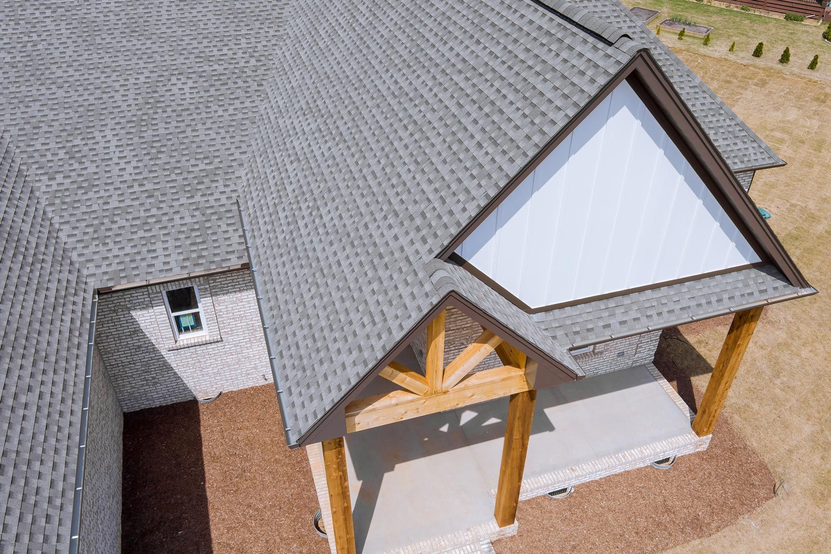 An aerial view of a house with a gray roof and a wooden porch.