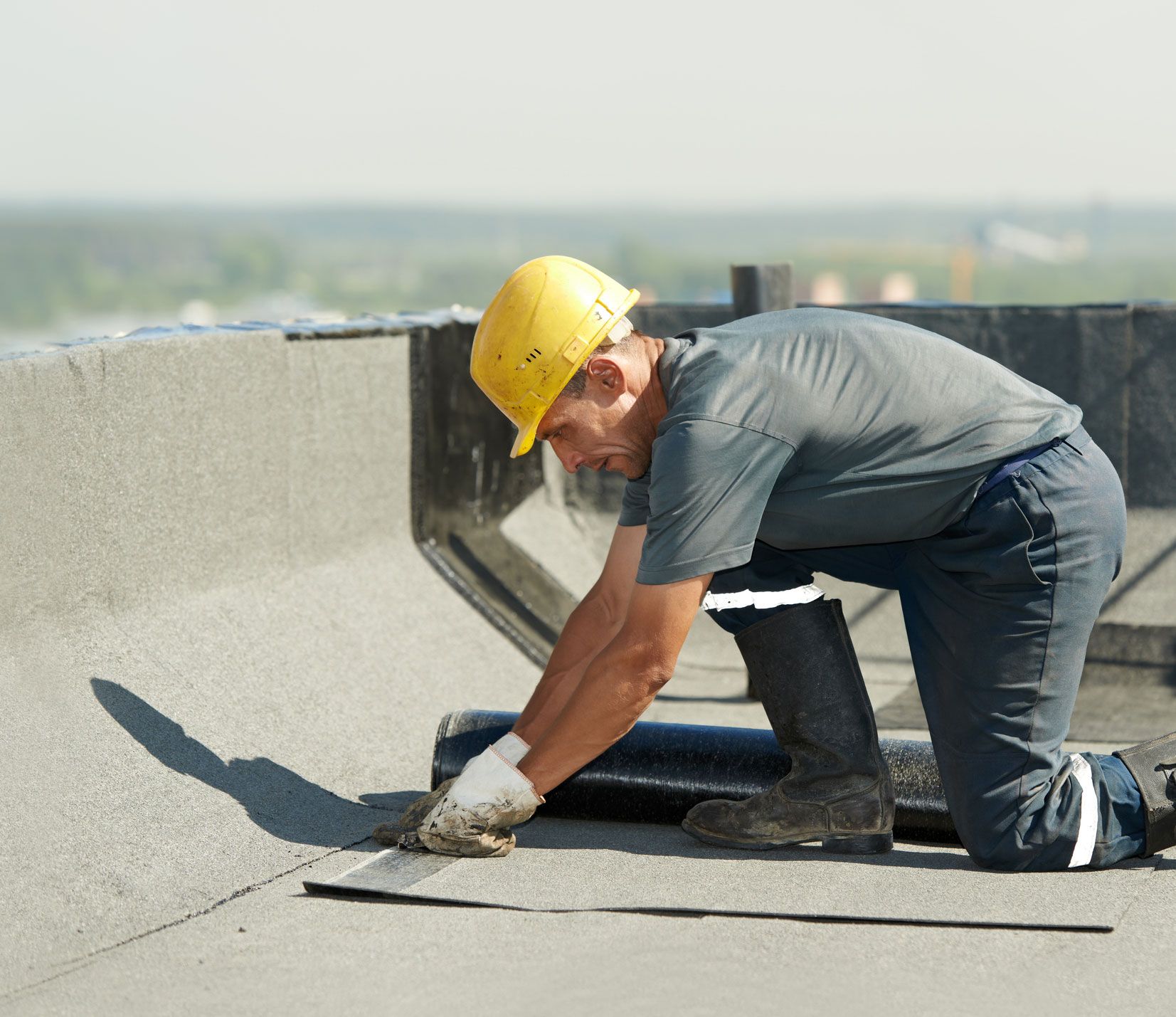 A man wearing a hard hat is working on a roof