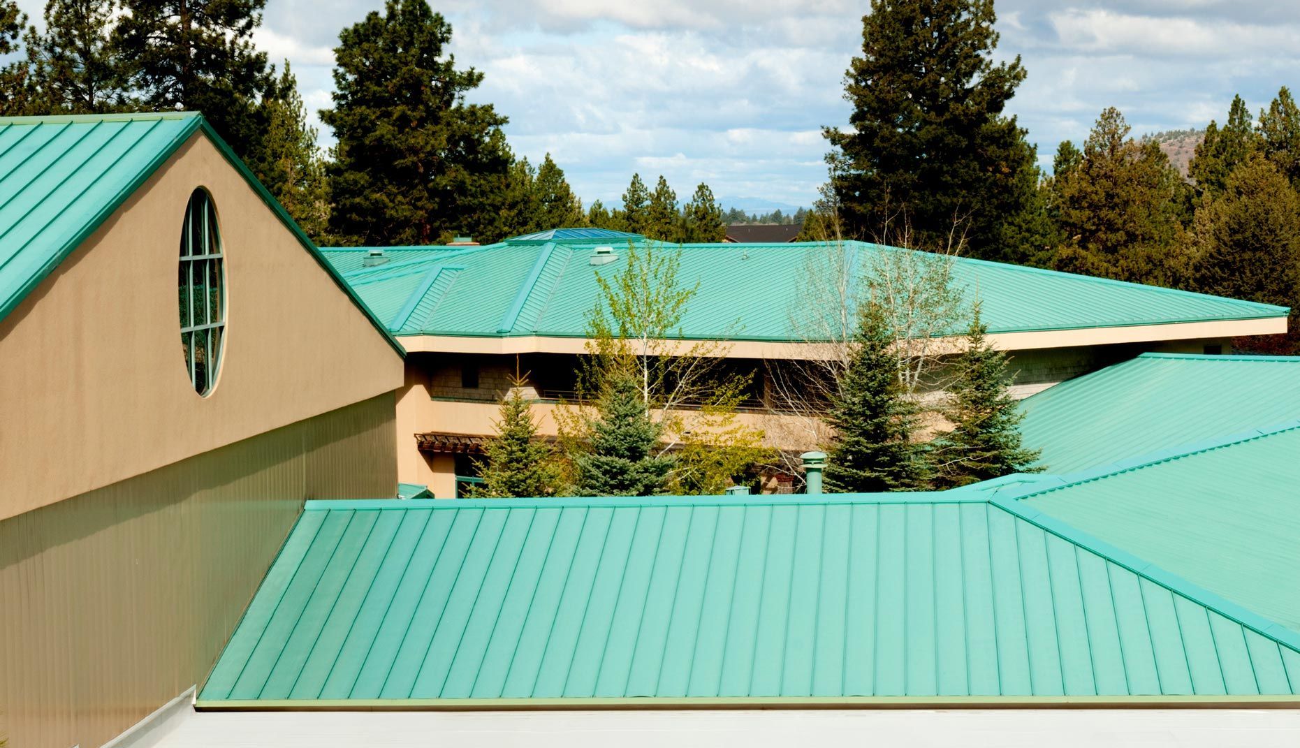 A building with a green roof and trees in the background