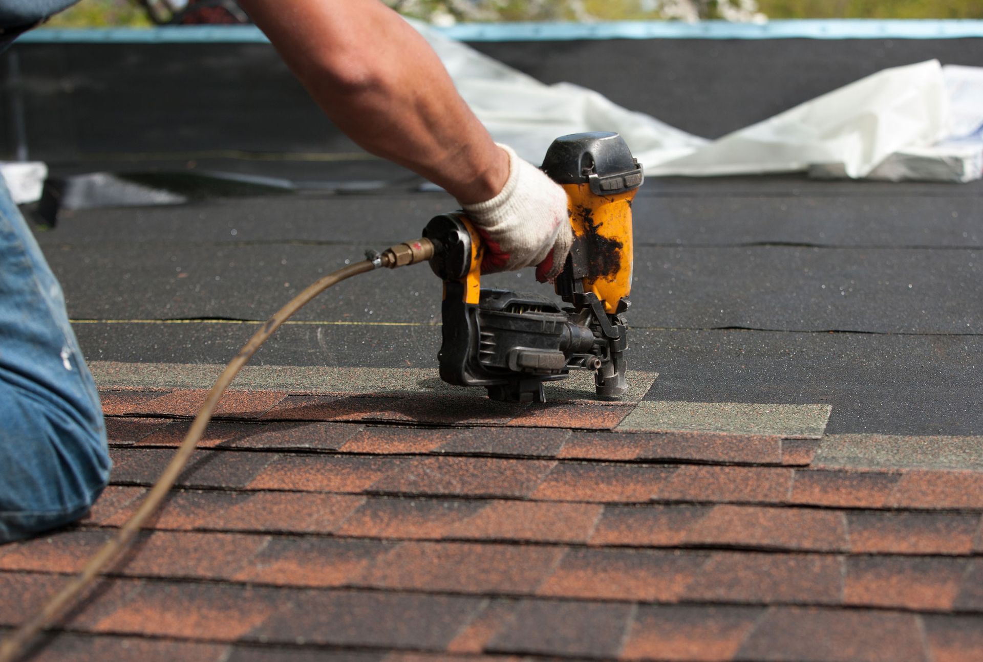 A man with a drill working on the roof of a house.