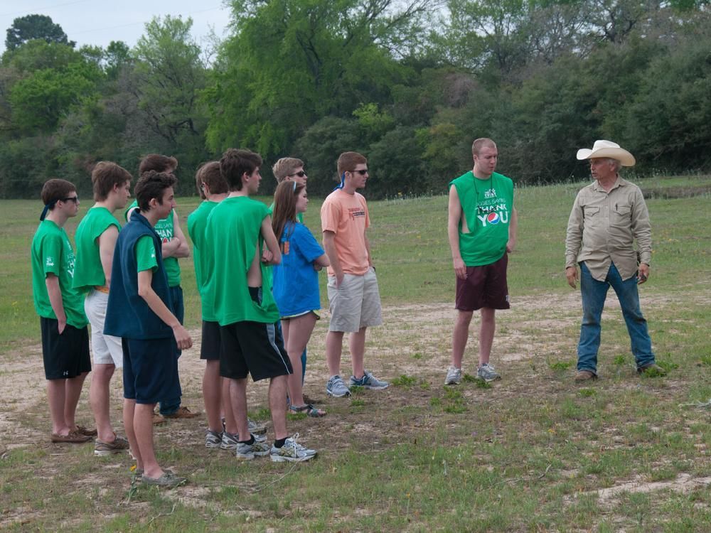 A man in a cowboy hat talks to a group of young people