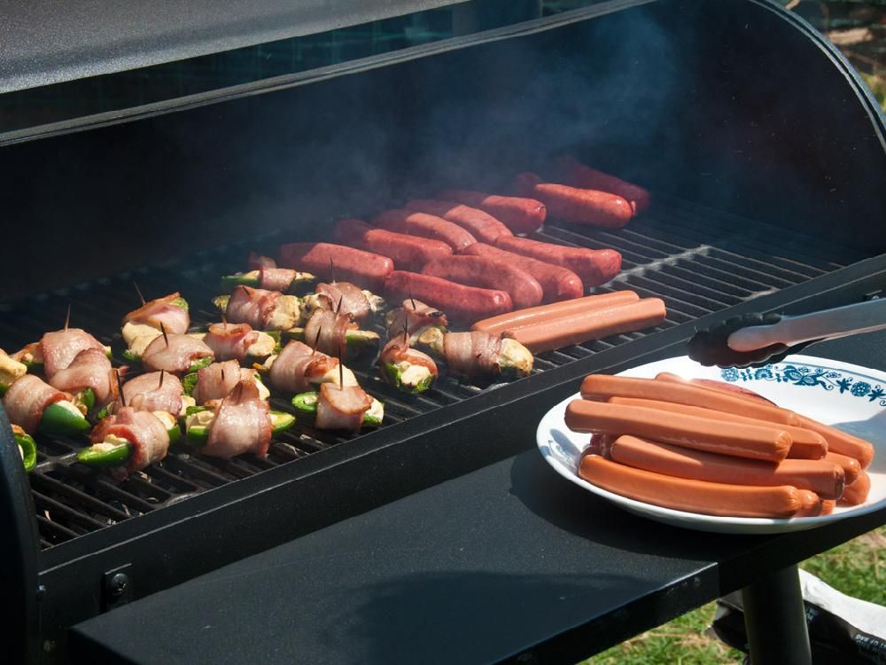 A grill with a plate of hot dogs next to it