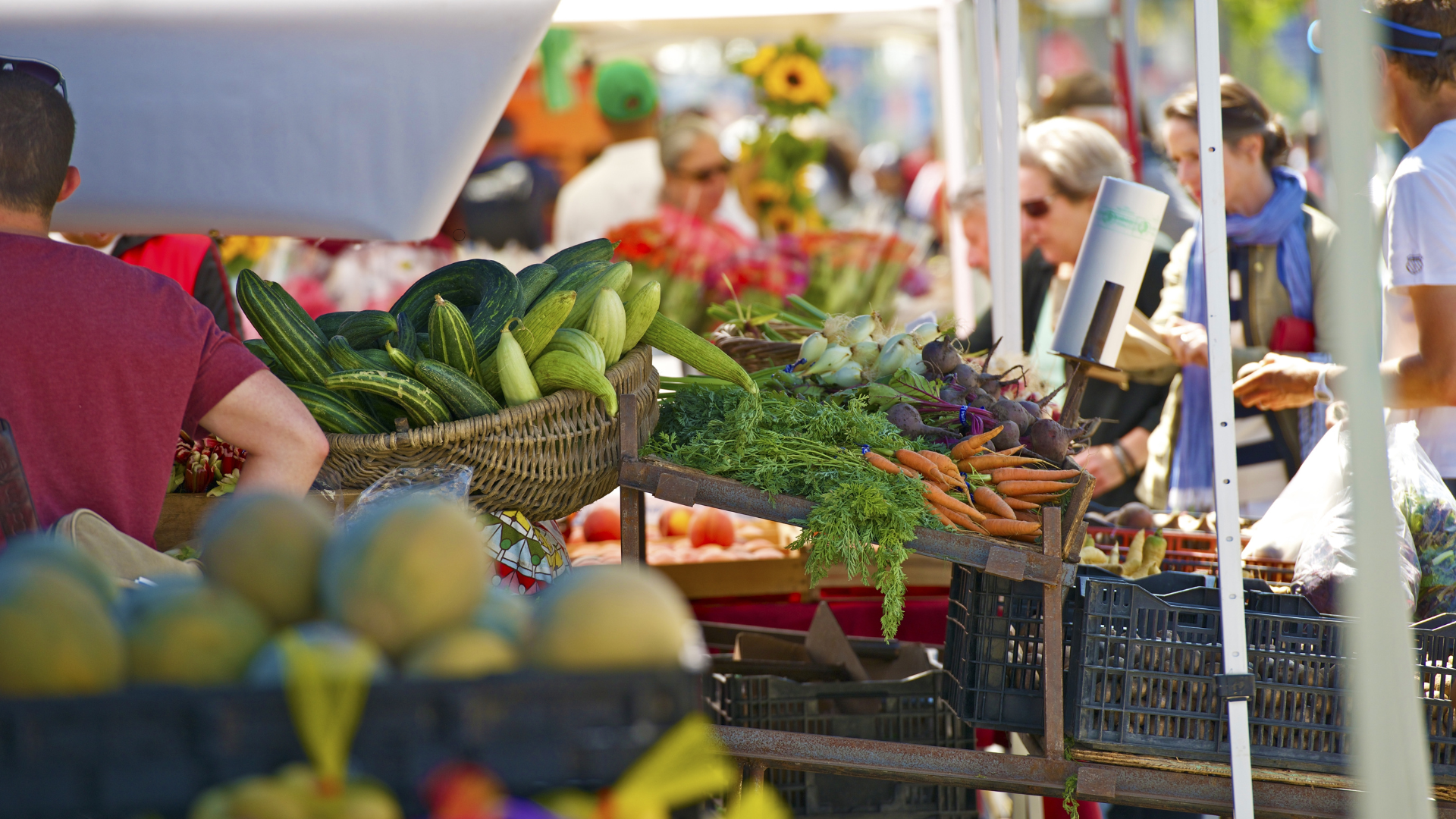 A group of people are shopping at a farmers market.