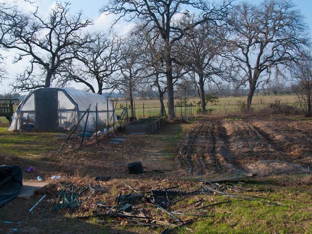 A greenhouse in the middle of a field with trees in the background