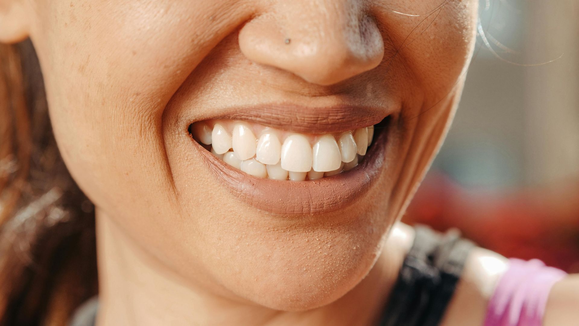 Nahaufnahme eines lächelnden Mundes mit strahlend weissen Zähnen und rosa Lippenstift