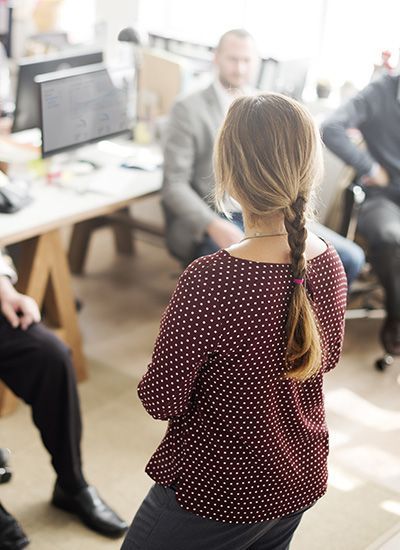 A woman is standing in front of a group of people in an office.