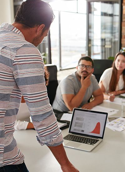 A man is giving a presentation to a group of people sitting at a table.