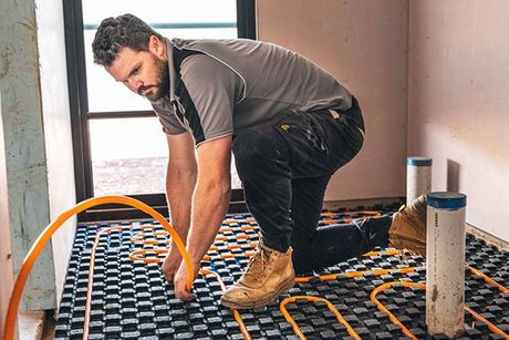 A picture of Bede, our owner, installing Hydronic Underfloor Heating in a home in Toowoomba