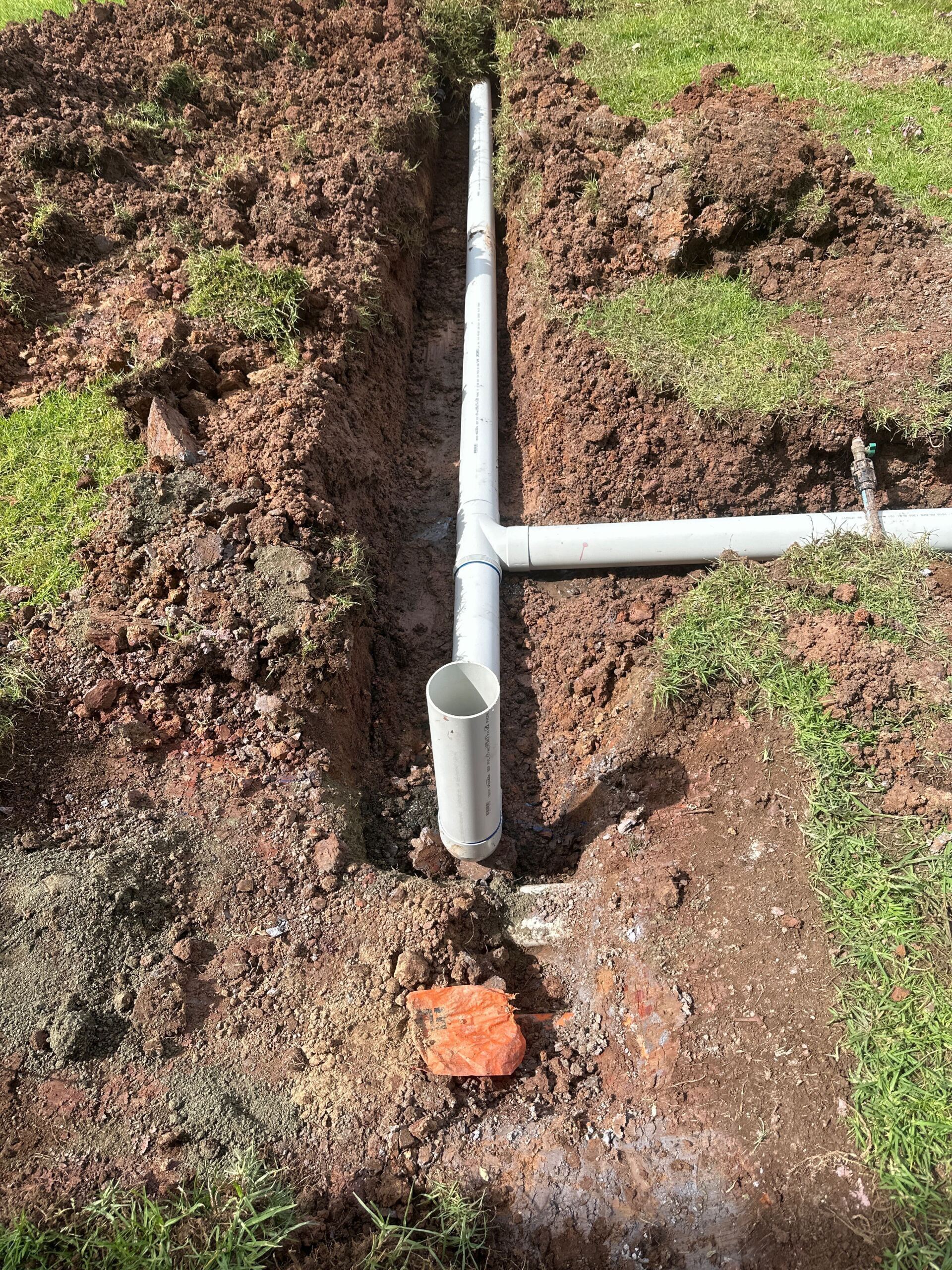 Stormwater drainage installation - trenches dug and pipe laid ready for back fill
