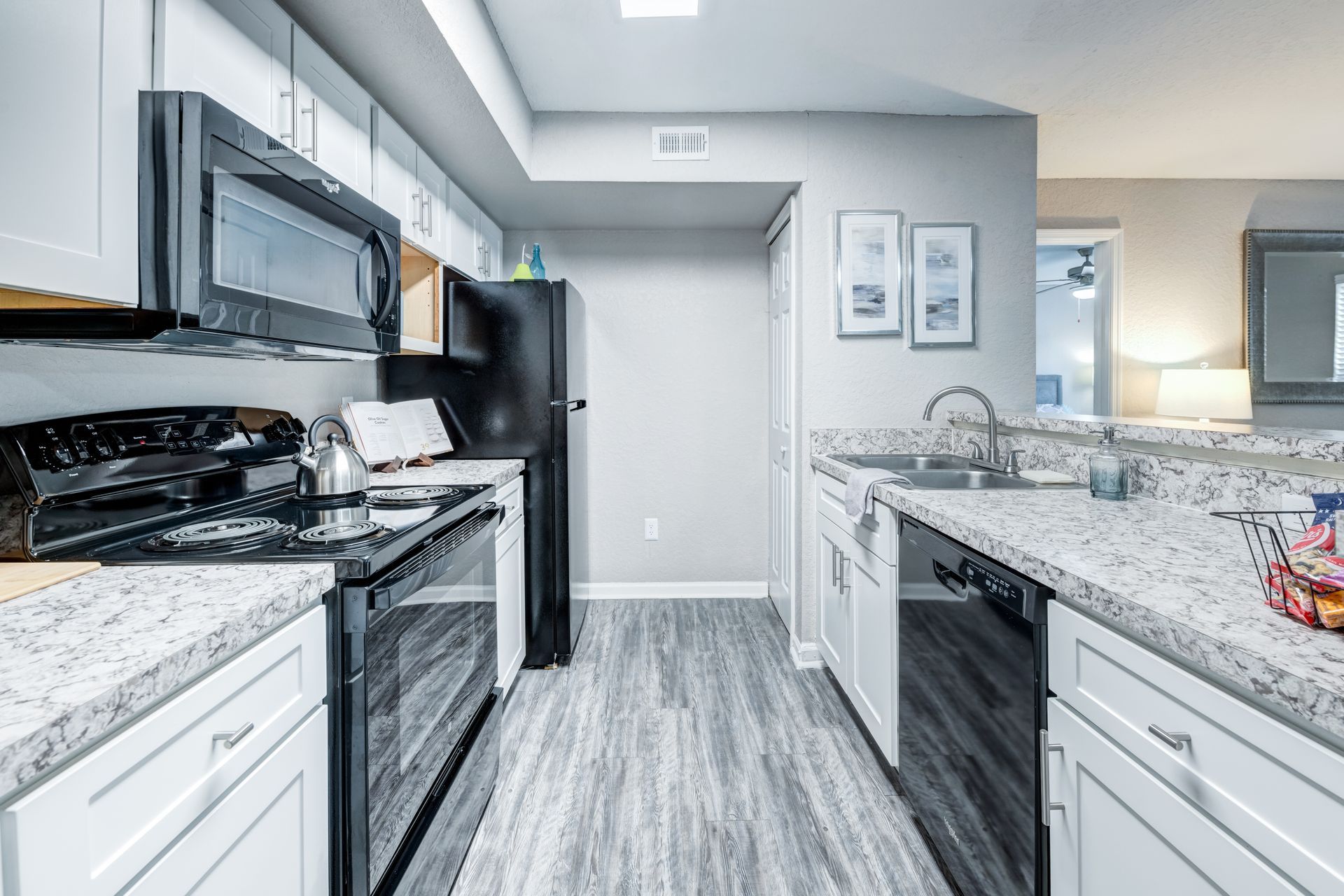 A kitchen with a stove , refrigerator , microwave and a mirror.