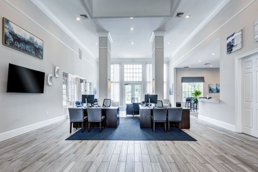 Reception area with desks, computers, chairs, artwork, and large windows.
